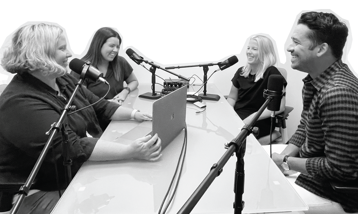 Four smiling people sitting around a table facing microphones